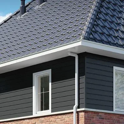 Keralit gevelbekleding op de donkere buitengevel van een woning met dakpannen en witte kozijnen