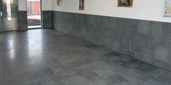 Tegelwerk op de vloer en de onderste helft van de wand in een ruime kamer.