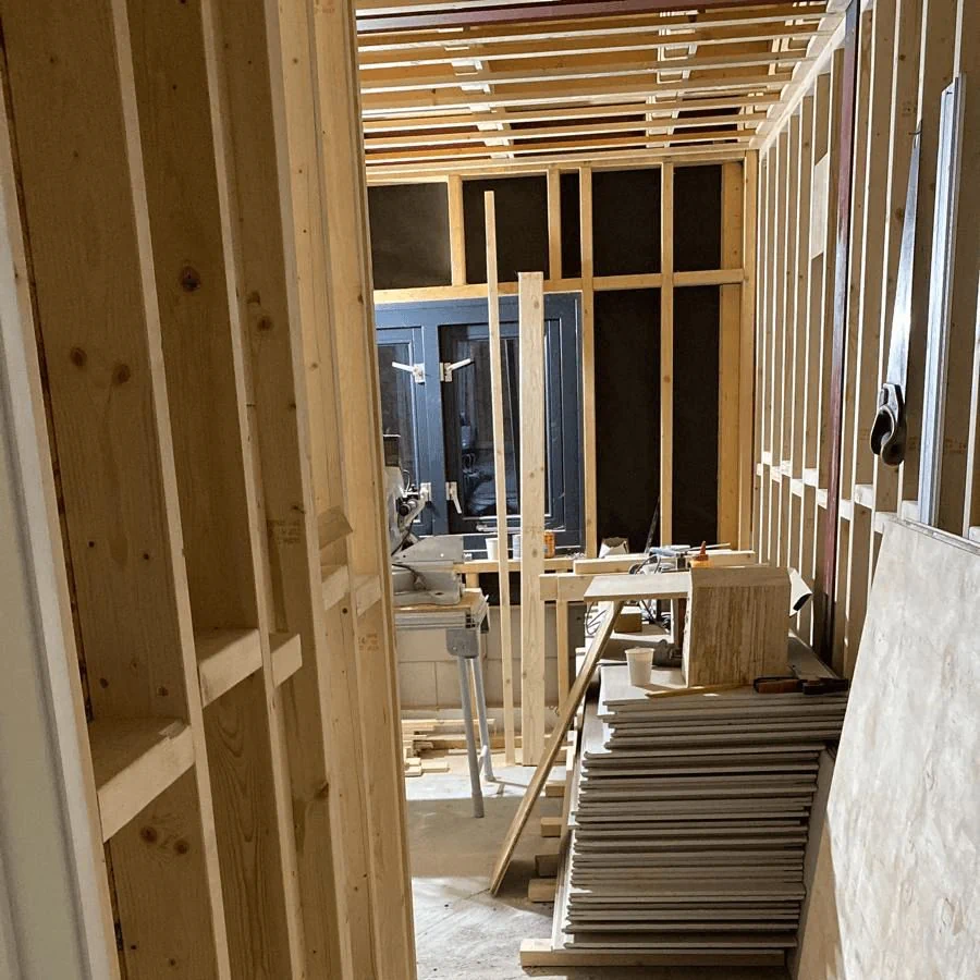 Timmerwerk met houten wandconstructie en bouwmaterialen in een binnenruimte.